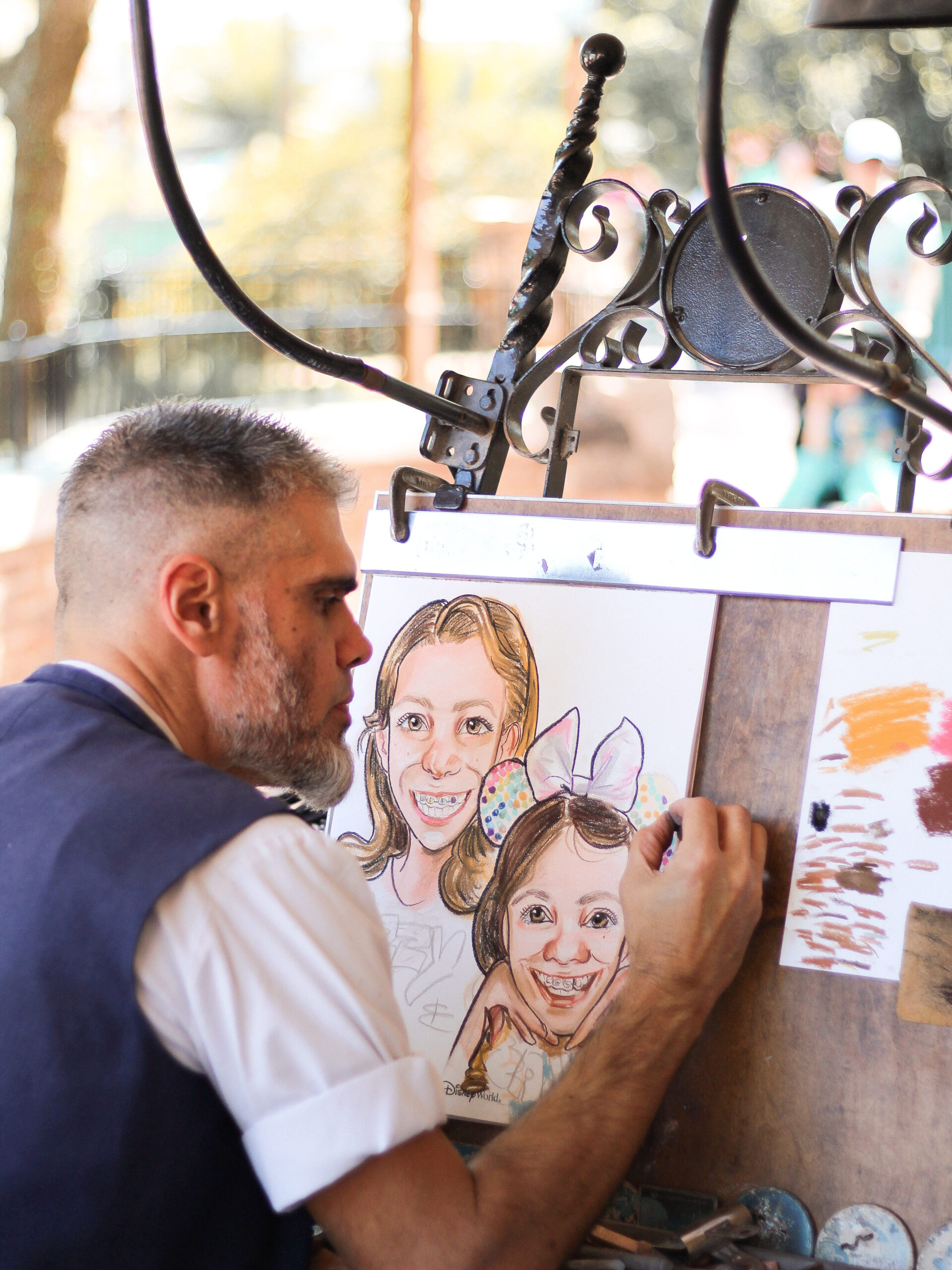 Caricature and portrait artist Elias sketching a caricature of two young girls at Magic Kingdom