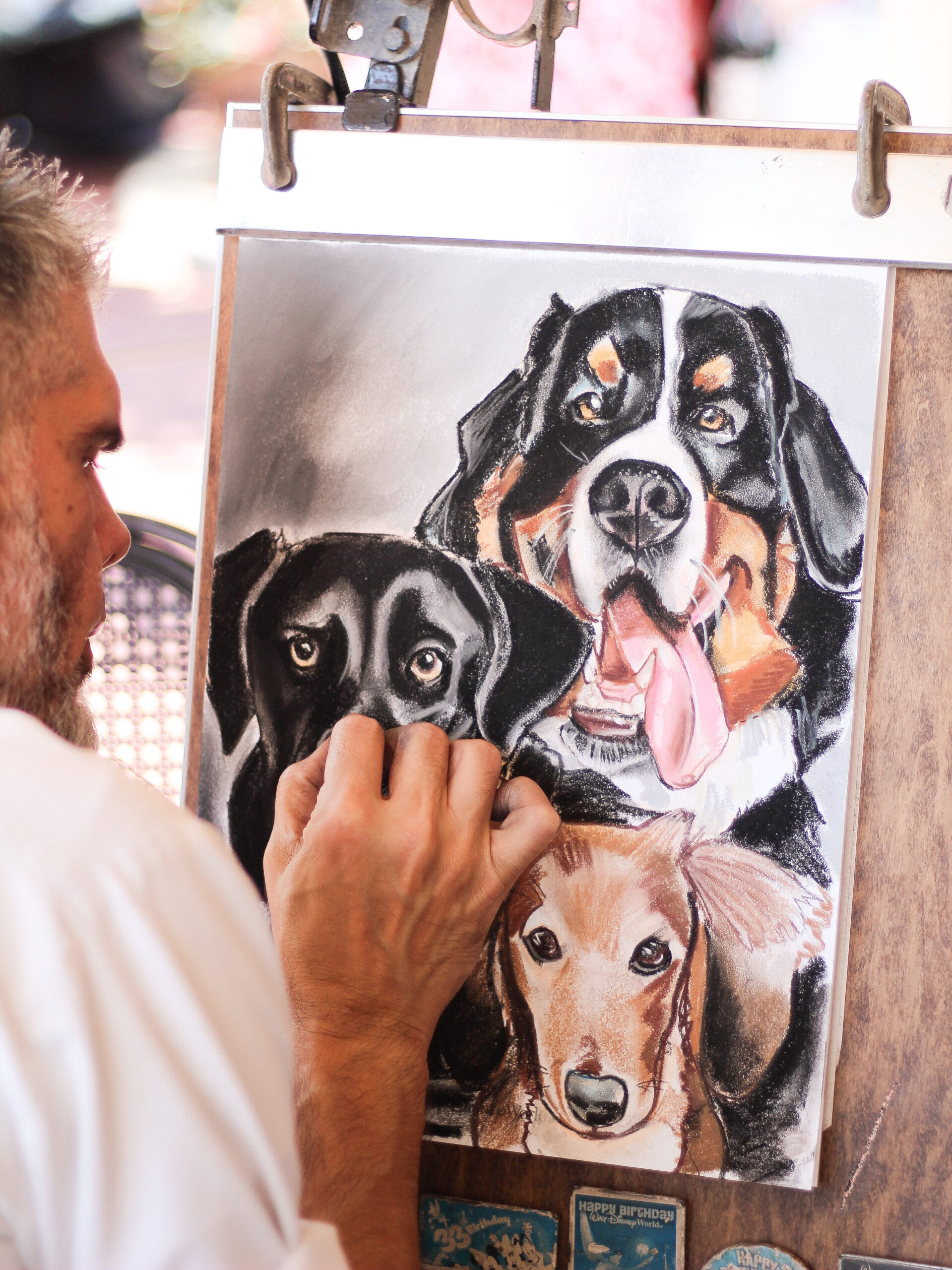 Caricature and portrait artist Elias sketching a portrait of three dogs at Magic Kingdom