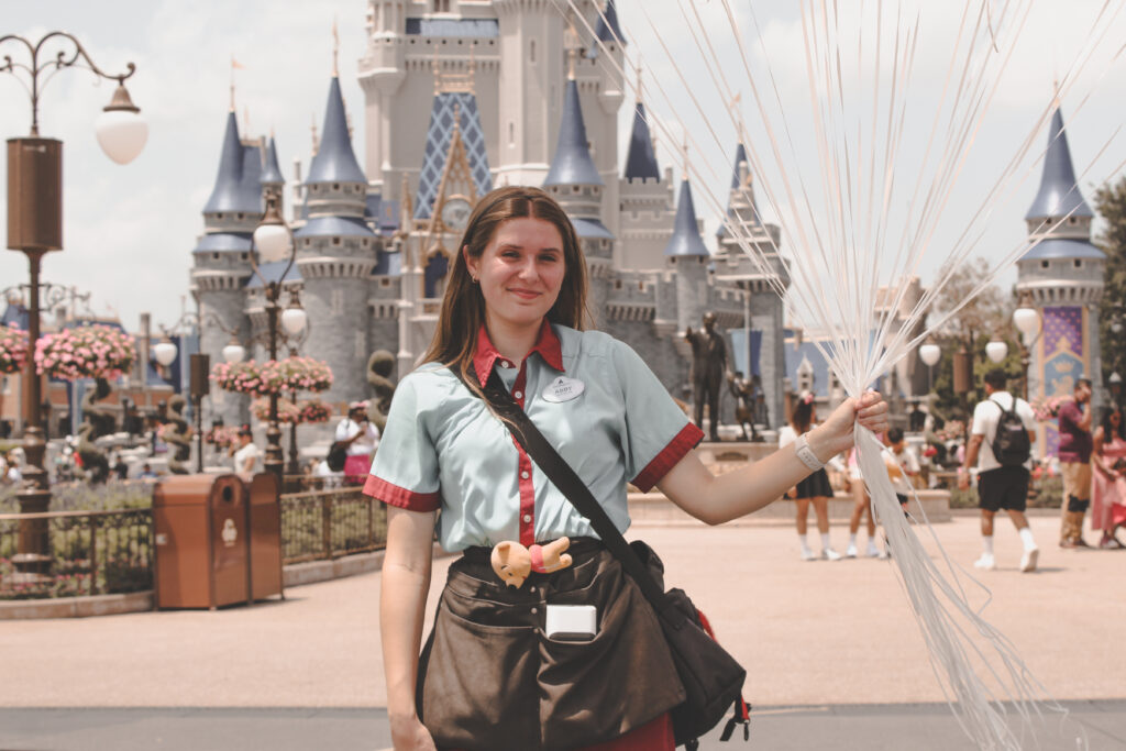 Walt Disney World balloon vendor cast member in front of Cinderella Castle